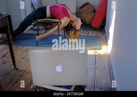 A woman at home doing yoga and watching an online class. Stock Photo