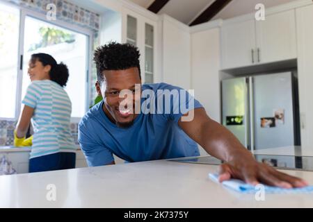 Happy african american couple cleaning countertop together in kitchen Stock Photo