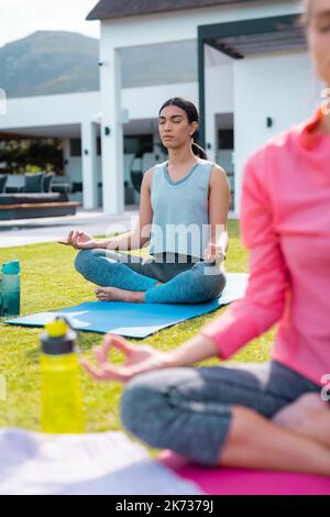 Diverse friends practicing yoga and meditating in garden Stock Photo