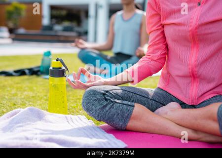 Diverse friends practicing yoga and meditating in garden Stock Photo