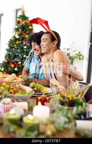 Happy diverse friends sitting at table and having dinner at christmas Stock Photo