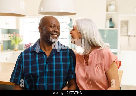 Happy senior diverse couple in kitchen smiling Stock Photo