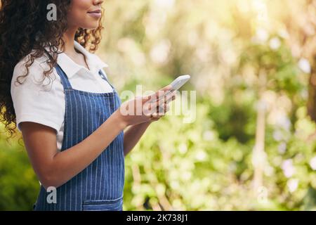 Bring the items to you. a florist using her smartphone to send a text message. Stock Photo