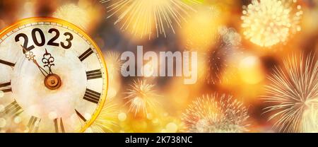 2023 New Year with fireworks and clock counting down to midnight with defocused golden background Stock Photo