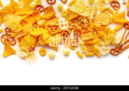 Salty snacks on white. Potato and tortilla chips, salt crackers etc, shot from the top with copy space. Party food mix Stock Photo