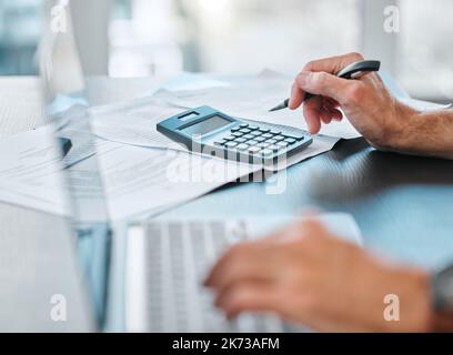 Its time to calculate my weekly budget. an unrecognisable businessman sitting alone in his office and using his laptop while calculating his finances. Stock Photo