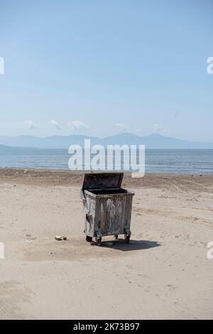 A big metal trash bin on an empty beach. Stock Photo