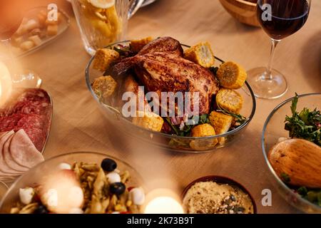 Close up of roasted chicken on dinner table with rustic homemade dishes in cozy setting Stock Photo