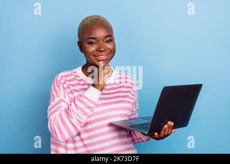 Closeup photo of young thoughtful attractive girl wear pink striped pullover looking camera isolated on blue color background Stock Photo