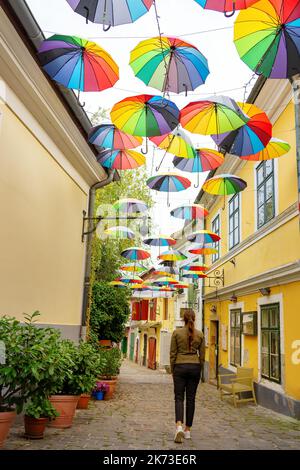 tourist woman walking on the streets of Szentendre under colorful umbrellas Stock Photo