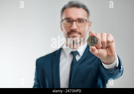 The digital currency taking the world by storm. Studio shot of a mature businessman holding a bitcoin against a white background. Stock Photo