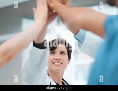 Lets tackle this day. a group of doctors giving each other a high five at work. Stock Photo