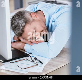 Hard work is too tiring. a mature businessman sleeping at his desk in an office. Stock Photo