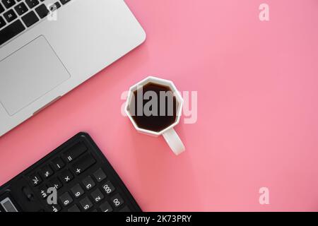 Office background with coffee, laptop on pink background. Stock Photo