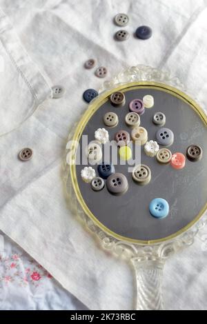Vintage buttons on an antique mirror on top old linens Stock Photo