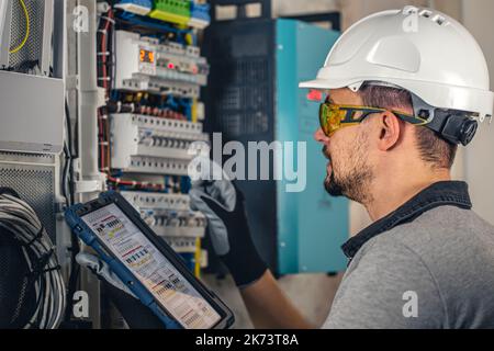 Man, an electrical technician working in a switchboard with fuses. Stock Photo