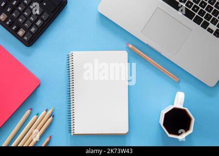 Flat lay, notepad, laptop and stationery on blue background. Stock Photo
