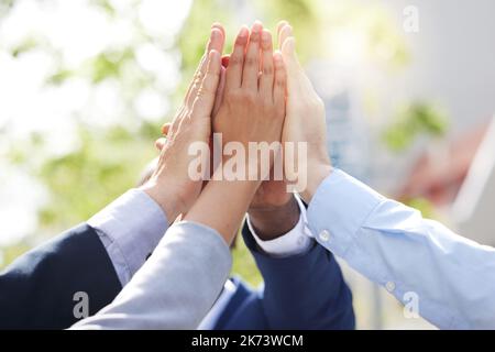 I know we can. a group of unrecognizable businesspeople giving a high five outside. Stock Photo