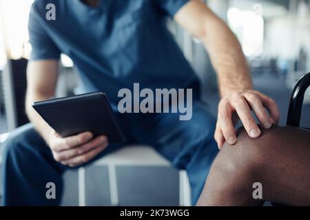 Close-up of doctor using digital tablet while examining pain leg of patient Stock Photo