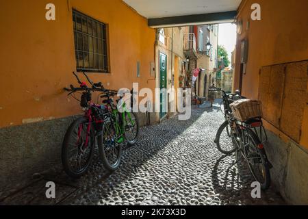 Alley Italy, view in summer of bikes parked in a picturesque alley in the colorful Old Town area of Bellagio in Lake Como, Lombardy, Italy Stock Photo