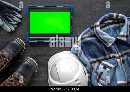 Digital tablet with layout and worker clothes, top view. Stock Photo