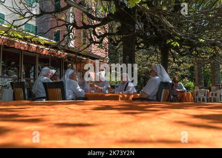 A group of Roman catholic nuns sat  around a table chatting, Montallegro Northern Italy ITA. September 2022. Stock Photo