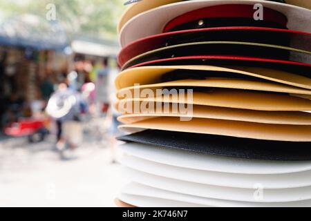 Stack of straw hats on street store. Men colorful accessories piled up, souvenir concepts Stock Photo