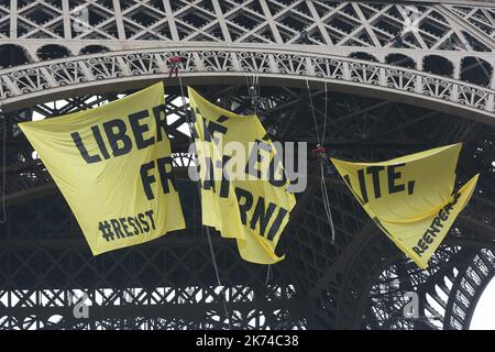 FRANCE, Paris: A Greenpeace activist hangs from a cord after unveiling a banner reading liberty, equality, fraternity on the Eiffel Tower in Paris early on May 5, 2017, to protest against the far-right Front National (FN) party, two days before the second round of the presidential election. Stock Photo