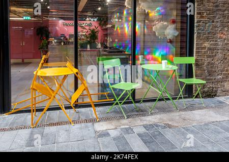 Green and orange metal chairs and tables outside a cafe in Camden Town, London, UK Stock Photo