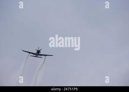 Plane climbing up with smoke at back within dark clouds Stock Photo