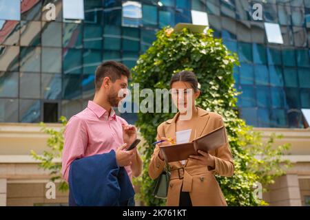 A young business couple are working outside in the city, having nice conversation, on a beautiful sunny day Stock Photo
