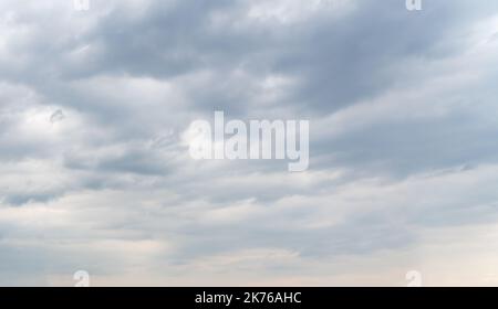 Smooth rows of gray clouds block out the sunlight Stock Photo