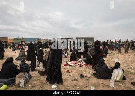 The Kurdish YPG of the coalition (Syrian Democratic Forces AKA SDF) are taking thousands of women and children of Daesh jihadists (ISIS) out of Baghouz, the last jihadist stronghold in Syria, in trucks to drop them at Al Hol camp a few hours away. Stock Photo