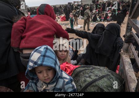 The Kurdish YPG of the coalition (Syrian Democratic Forces AKA SDF) are taking thousands of women and children of Daesh jihadists (ISIS) out of Baghouz, the last jihadist stronghold in Syria, in trucks to drop them at Al Hol camp a few hours away. Stock Photo