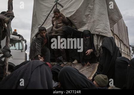 The Kurdish YPG of the coalition (Syrian Democratic Forces AKA SDF) are taking thousands of women and children of Daesh jihadists (ISIS) out of Baghouz, the last jihadist stronghold in Syria, in trucks to drop them at Al Hol camp a few hours away. Stock Photo