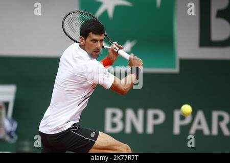 Novak Djokovic of Serbia plays a backhand during his mens singles semi-final match against Dominic Thiem of Austria on day fourteen of the 2019 French Open at Roland Garros in Paris Stock Photo