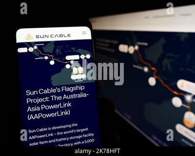 Person holding mobile phone with website of energy company Sun Cable Pty. Ltd. on screen with logo. Focus on center of phone display. Stock Photo