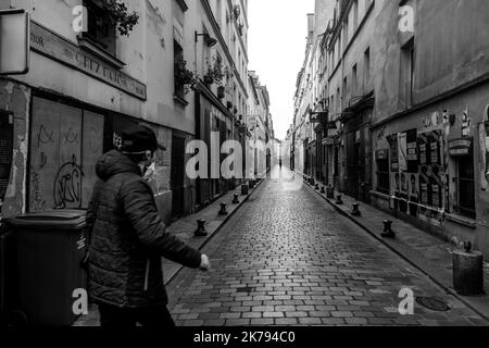 A man walks past the almost empty rue de Lappe. It is 4:37 p.m. First day of confinement for the French after the announcement of President Emmanuel Macron. Since noon, the movements of the French have become limited. Exceptional measures to try to stop the spread of Coronavirus, covid-19. Paris, France. March 17, 2020. Stock Photo