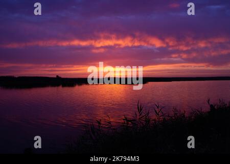 Beautiful sunrise over the river. Magical sunrise behind colorful clouds over the lake. Calm water in a pond on the backdrop of a bright sky with a ri Stock Photo
