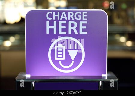 Public electrical charging station, Charge Here sign, device recharging area, power outlets Stock Photo