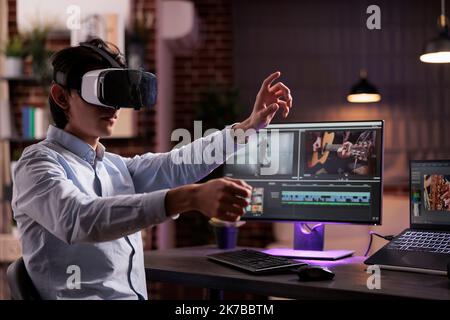 Man using vr glasses to edit film footage with computer software app. Videographer editing movie montage with visual and sound effects, creating video for multimedia production. Stock Photo