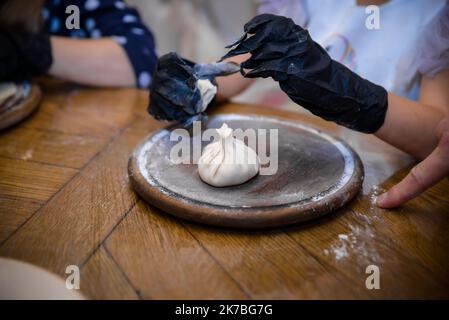 The hands of an old grandmother mold vareniks on a dark background Stock Photo