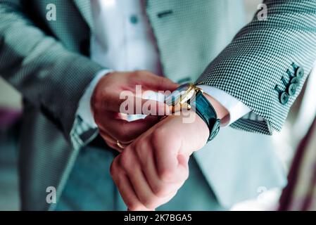 businessman checking time on his wrist watch, man putting clock on hand,groom getting ready in the morning before wedding ceremony Stock Photo