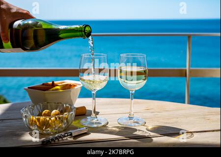 Pouring of txakoli or chacolí slightly sparkling very dry white wine produced in Spanish Basque Country, served outdoor with view on Bay of Biscay, At Stock Photo