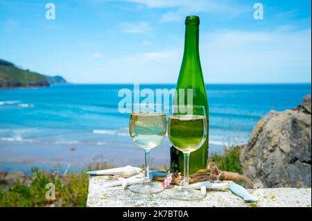 Tasting of txakoli or chacolí slightly sparkling very dry white wine produced in Spanish Basque Country, served outdoor with view on Bay of Biscay, At Stock Photo