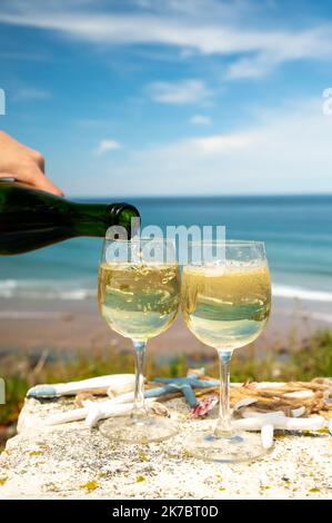 Tasting of txakoli or chacolí slightly sparkling very dry white wine produced in Spanish Basque Country, served outdoor with view on Bay of Biscay, At Stock Photo