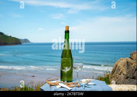 Tasting of txakoli or chacolí slightly sparkling very dry white wine produced in Spanish Basque Country, served outdoor with view on Bay of Biscay, At Stock Photo