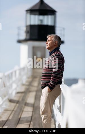 Senior man leaning on the fence looking ahead thoughtfully Stock Photo