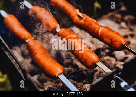Sausages close-up on the grill on fire, against the background of smoke. Meat and snacks, food and fast food Stock Photo