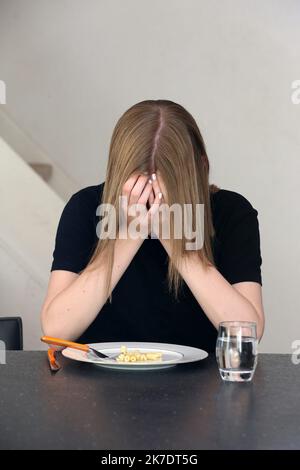 ©PHOTOPQR/L'ALSACE/Vanessa MEYER ; ; 02/06/2021 ; Une jeune fille anorexique devant une assiette de pâtes presque vide et un verre d'eau tient sa tête entre ses mains. Les troubles du comportement alimentaire ont augmenté pendant la crise sanitaire. - anorexia Stock Photo